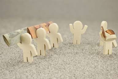 Foto: Kleine Figuren mit Geldscheinen und Münzen