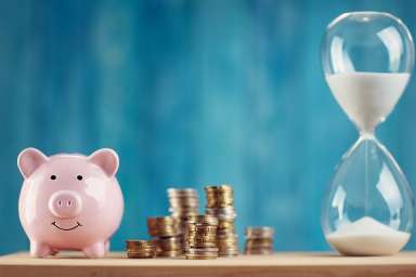 Foto: Sparschwein mit Münzen und Sanduhr